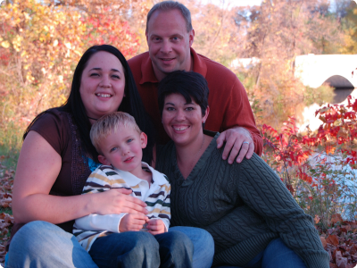 een familiefoto met een jongen, zijn biologische moeder en zijn adoptieouders.