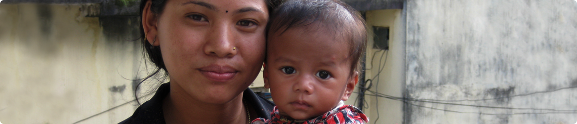 A care giver holds an infant in an alley in Nepal.