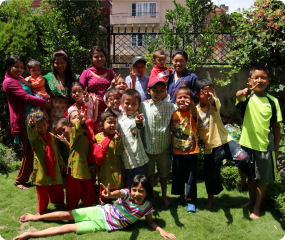 Children in brightly colored clothes at ISN smile for a group picture.