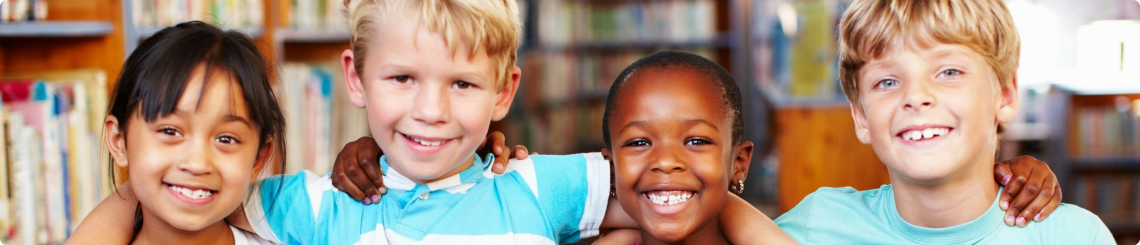 Four kids of different races smile in a group.