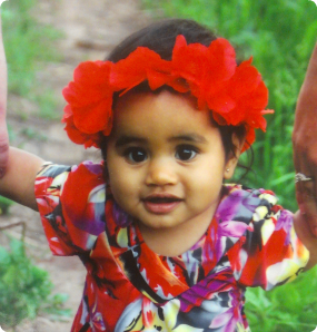 A beautiful photo of a girl adopted from RMI wearing a headband made of flowers and a traditional dress.