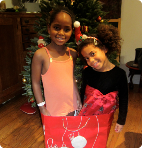 Meski, adopted from Ethiopia, and her sister Tania, adopted from Colombia, goof around by taking a picture in a giant gift bag.