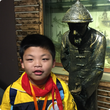 YF, who waits to be adopted from China, stands in front of a statue.