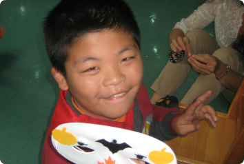 A picture of YF smiling while making masks with orphanage volunteers.