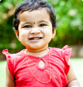 An adorable toddler from India grins at the camera.