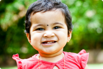 An adorable toddler from India grins at the camera.