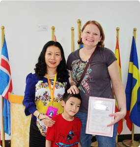 Kathy and her son during the adoption process pose in front of flags.
