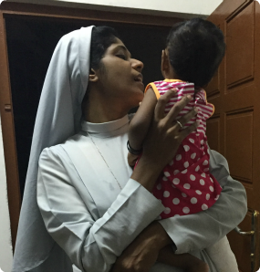 An orphanage caregiver, a nun, holds a child at an orphanage.