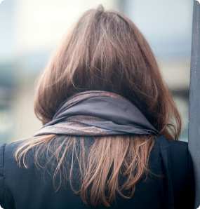 The back of a woman's head as she looks down the street.