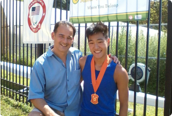 A picture of Isaac, an adoptee with a limb difference, and his father at a bayada for adaptive rowers.