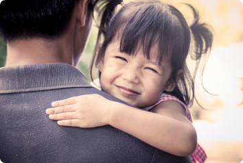 A girl adopted from China smiles in her father's arms.