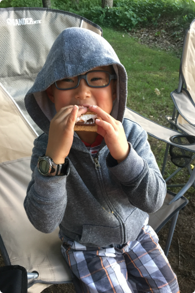 A young boy adopted from South Korea eating a s'more.
