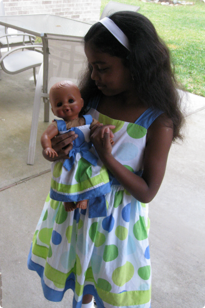 A young girl adopted from India with her doll in a matching outfit.
