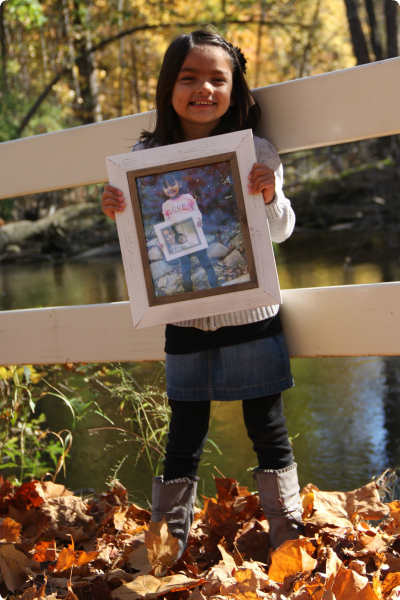 A young girl adopted from India holds pictures of herself over the years.