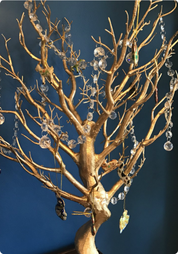 A picture of a golden tree branch with zodiac ornaments and crystals dangling from it. A new tradition created to celebrate the Chinese New Year in Jennifer's family.