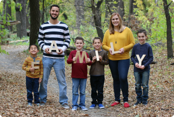 Each member of the family, created through foster care, smiles at the camera and holds a letter so that it reads "Family"