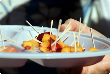 A close up of a plate of peaches cut up with toothpicks for customers to try at the grocery store.
