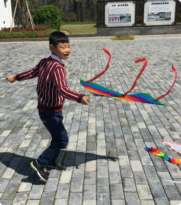 YK runs around the courtyard of his orphanage with a kite.