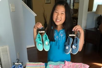 Kate, an 11-year-old Korean adoptee, holds up baby shoes she bought with her birthday money to donate to Korean foster care.