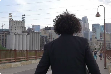 A picture of Clayton walking away from the camera as he crosses a bridge. 