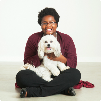 A picture of Thelma smiling while holding a white dog in her lap.She waits in Minnesota foster care for adoption.
