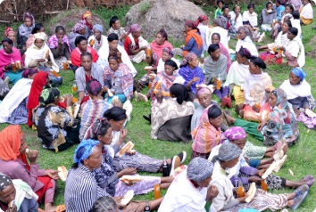 A large group of women in a self-help group in Ethiopia are pictured sitting in the grass.