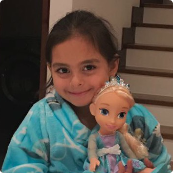 M is pictureed in a teal blanket holding an Elsa doll. She waits in Latin America for a family.