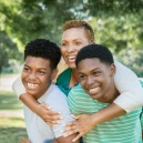 An African American single woman wraps her arms around two brothers she adopted from foster care.
