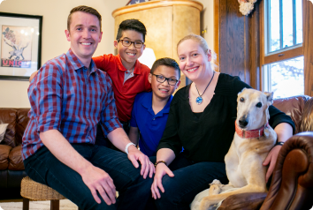The family is pictured on the couch in their living room sitting with their two sons adopted from China and their dog.