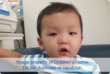 Infant boy sitting on the couch waits for adoption in Asia