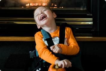 Christian laughs heartily in front of a fireplace.
