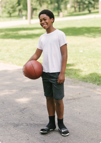 Dayshawn smiles while holding a basketball. He waits for an adoptive family.