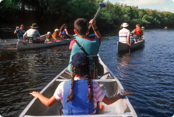 Two kids being hosted during Kidsave canoe down the river with their host family.
