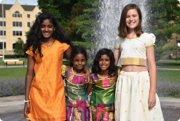 Girls of different ages at Camp Masala smile in traditional Indian clothing.