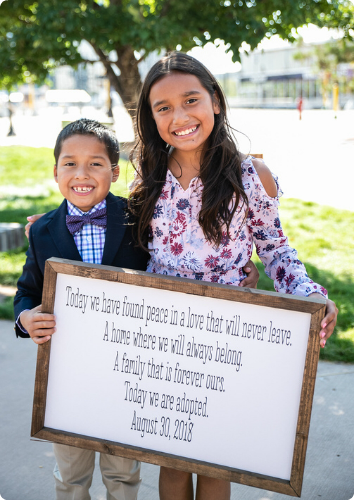 Kelly's kids hold a sign on their adoption day, "today we are adopted."