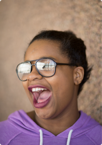 Thelma laughs boldly in a purple sweatshirt. She's at risk of aging out of foster care.