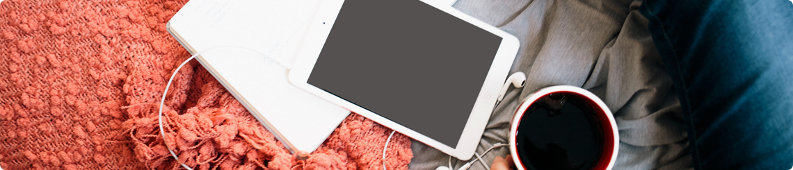 A computer, iPad and cup of tea are pictured on a bed.