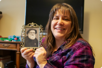 Christina smiles while holding a picture of her biological father, whom she met in her 40s.