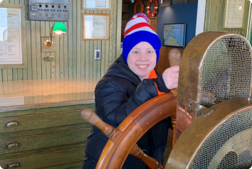 Sean at the helm of a ship during a springtime trip to the maritime museum. He waits in foster care for a family.