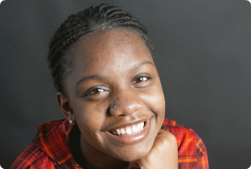 A teen waiting in foster care for adoption smiles brightly at the camera.