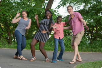 The family, created through foster care adoption, make funny faces in the park.