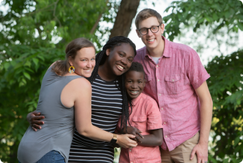 The foster care adoption family hugs each other and smiles for a photo.