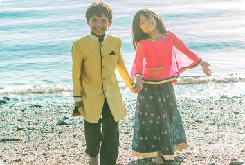 A brother and sister adopted together from India smile on the beach.