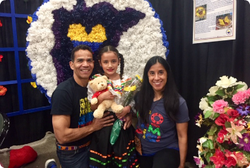 Monica and Miguel smile with their daughter who wears traditional Colombian clothes. All three were adopted from Colombia.