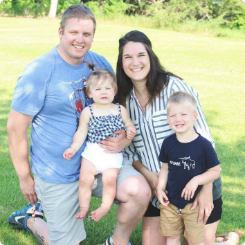 Bre, a former foster youth, smiles brightly with her husband and two children.