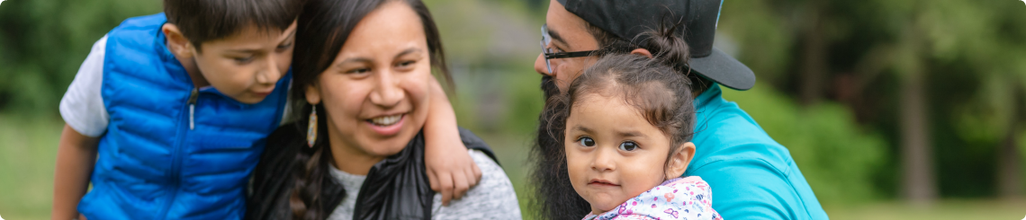 A native american couple smile with their foster kids, a brother who is in first grade and his toddler sister.