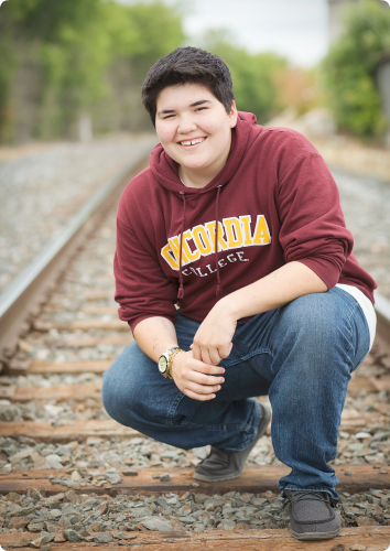 Genesis a teen waiting for an adoptive family in Minnesota foster care smiles on the railroad tracks.
