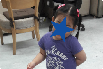 A censored photo of HN as she plays at a table. She waits in Asia for an adoptive family.