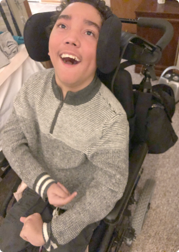A picture of Aaron sitting in his wheel chair and smiling. He waits to be adopted from foster care.