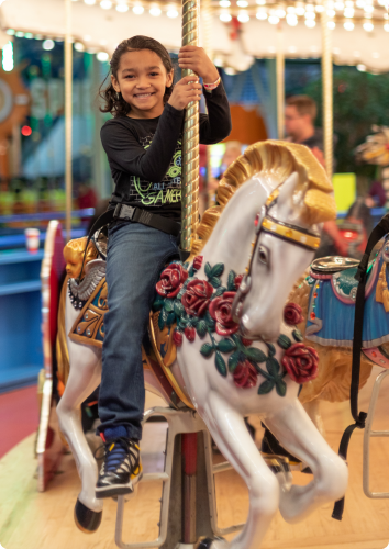 Ethan, who waits to be adopted from foster care, smiles on a carousel.